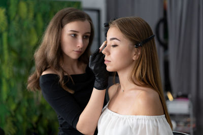 Close-up of of woman applying make-up to customer