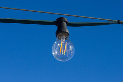 Low angle view of light bulb against blue sky