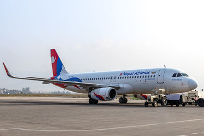 Airplane on airport runway against sky