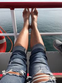 Low section of woman sitting on boat in sea