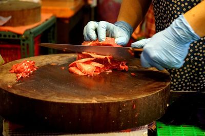 Cropped hands of person cutting meat at butcher shop