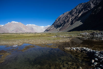 Scenic view of lake and mountains against blue sky