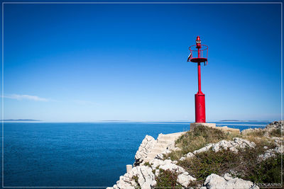 Lighthouse on beach against blue sky