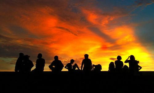 Silhouette people standing against sky during sunset