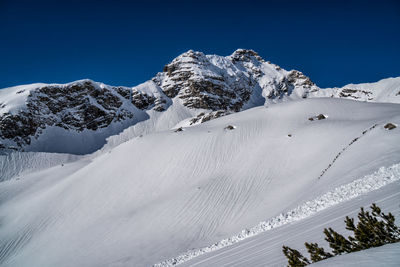 Scenic view of snow covered mountains against blue sky