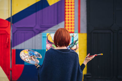 Rear view of woman holding multi colored umbrella