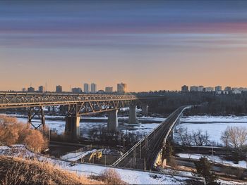 Bridge over river in city during sunset