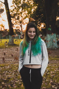 Smiling young woman standing on land during sunset