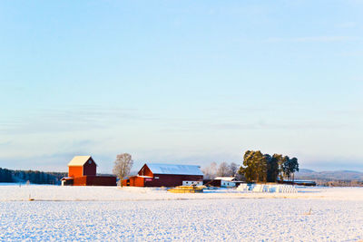 Houses on snow covered field against sky