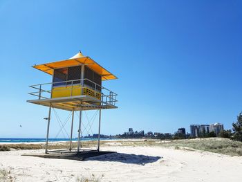Lifeguard hut on beach against clear blue sky
