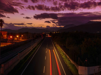 Light trails on road in city against sky at night