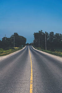 Road amidst trees against clear sky