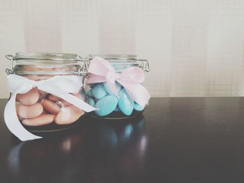 Food in glass containers with ribbons on table against wall