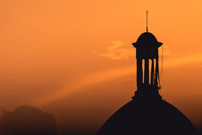 Silhouette cross against sky during sunset