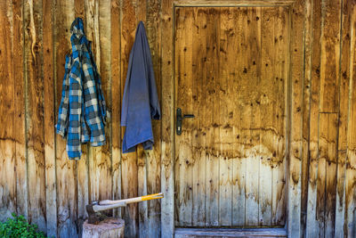 Two wooden axes stuck in the wood chopping trunk. in the background, a wooden wall of the old house.