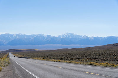 Road leading towards mountains against sky