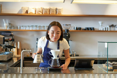 Portrait of young woman using mobile phone in cafe