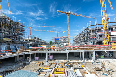 Cranes at construction site against sky