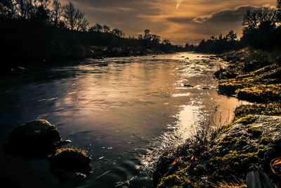 Scenic view of river against sky at sunset