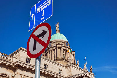 Low angle view of building against blue sky with teaffic signs