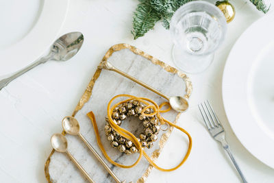 Christmas wreath of golden bells in the decoration of the festive dinner. cutlery on a marble board