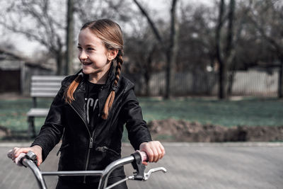 Smiling girl with bicycle at park