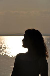 Woman standing at beach against sky during sunset