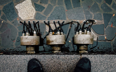 Low section of person standing by machines on wet footpath