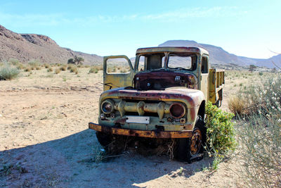 Abandoned car on field against sky