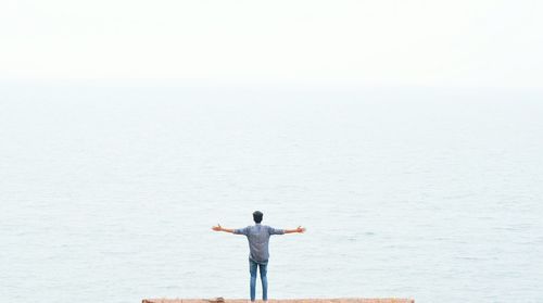 Rear view of man standing on sea against sky
