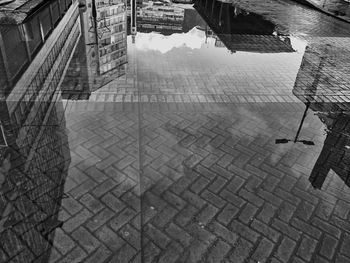 High angle view of buildings by street mirroring in puddle after the rain