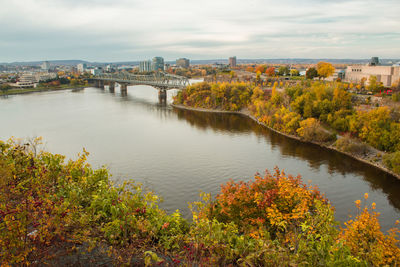 Arch bridge over river in city against sky