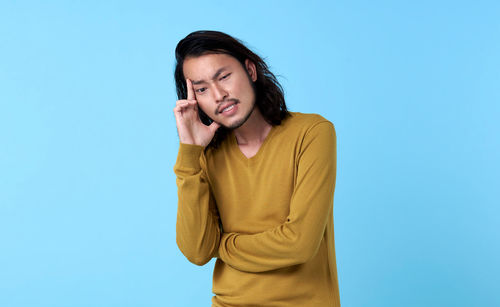 Mid adult man using smart phone against blue background