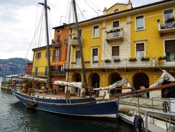 Sailboats moored on canal in city against sky