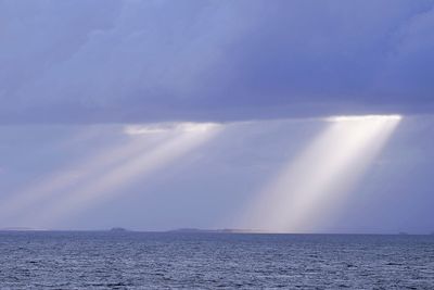 Sunlight streaming through clouds over sea