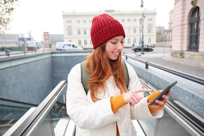 Portrait of young woman standing against building