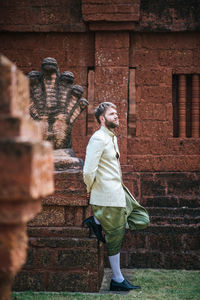 Side view of man standing against wall