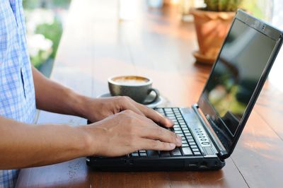 Midsection of woman using laptop on table