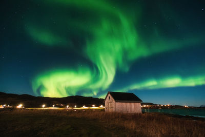 Low angle view of building against northern lights at night