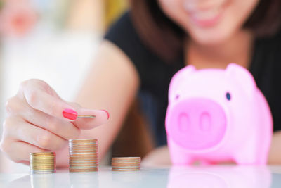 Midsection of woman stacking coins on table