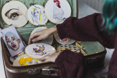 Female craftsperson arranging embroidery frames in suitcase