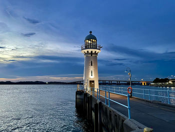 Lighthouse by sea against dark evening sky at dusk with no people