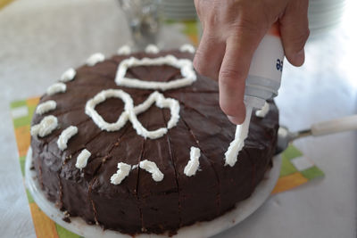 Cropped hand garnishing cake at home