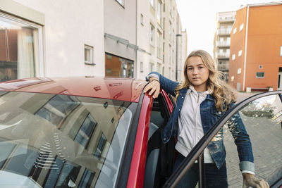 Portrait of teenage girl standing by car