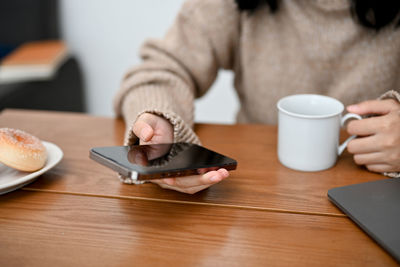 Midsection of woman using mobile phone on table