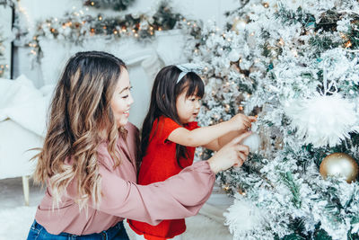 Portrait of smiling young woman holding christmas tree