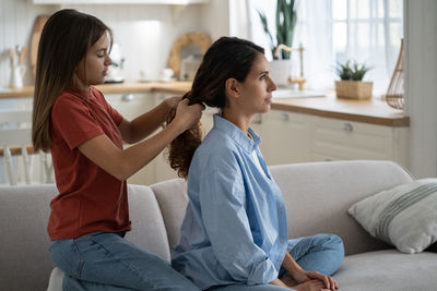 Side view of young woman using mobile phone at home