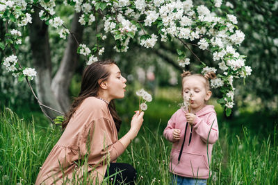 Mother and daughter with dandelions blooming apple trees