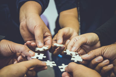 Cropped hands of people holding jigsaw puzzle