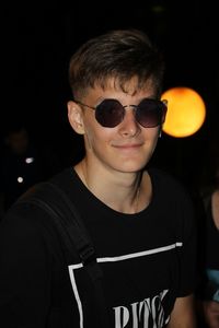Portrait of smiling teenage boy wearing sunglasses at night